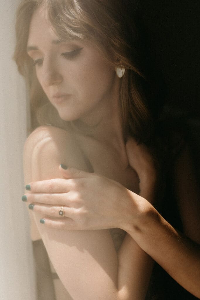 An intimate image of a woman embracing herself and staring out the window at Richmond, Virginia Boudoir studio