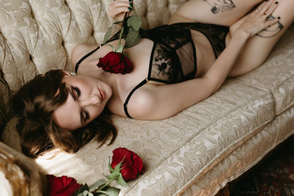 Image of a woman laying on a couch with a rose for her Pre Mastecomy Boudoir Session. 