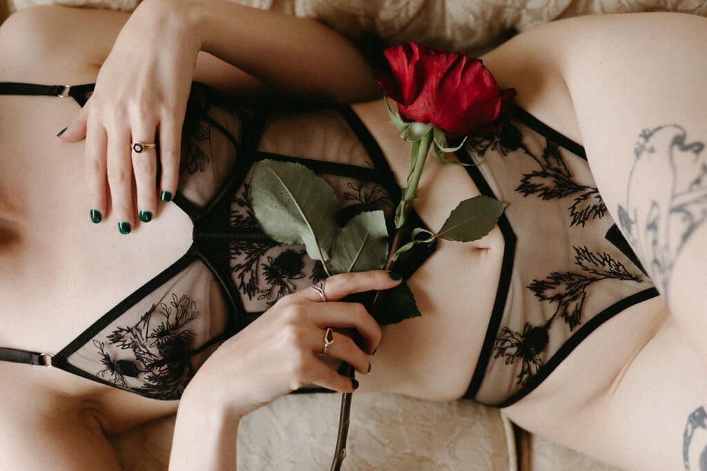 An intimate image of a woman's torso with a rose. 