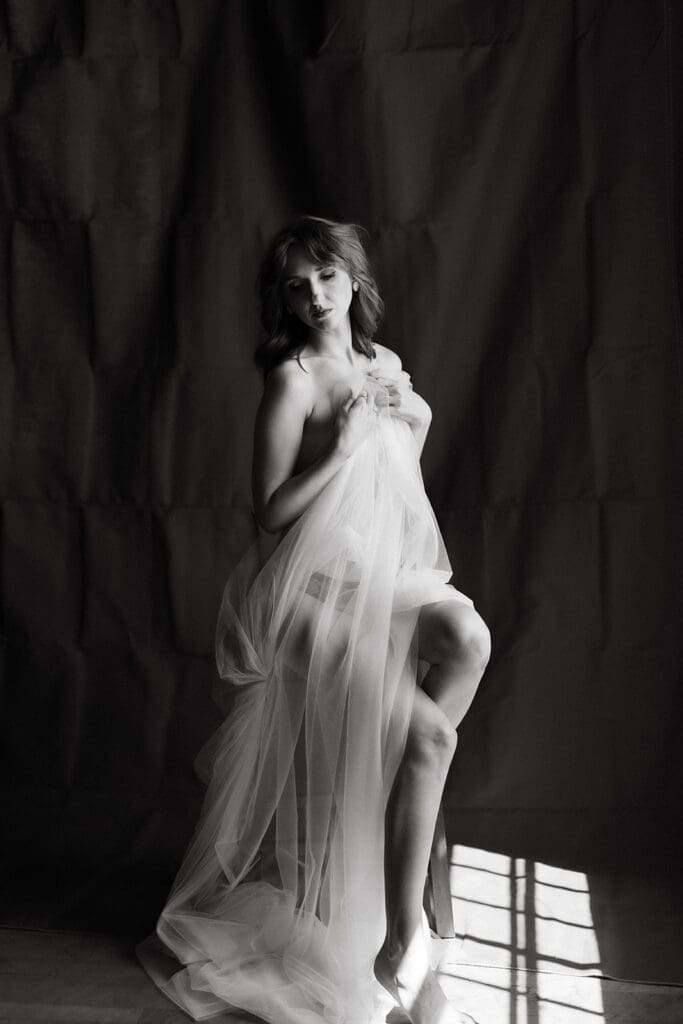 Whimsical black and white image of a woman wrapped in tulle.