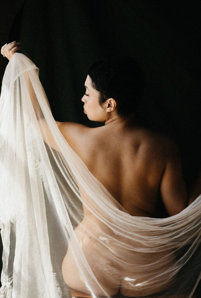 Portrait of a woman holding a tulle veil in front of a Fine Art Backdrop.